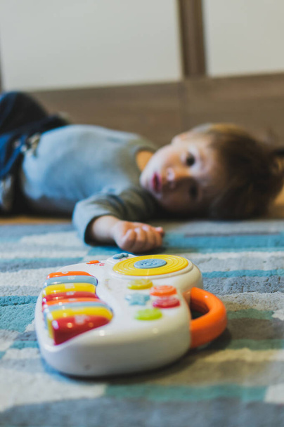 POZNAN, POLEN - 27. Okt 2018: Plastik-Spielzeug-Musiktastatur liegt auf einem Teppich neben einem Kind im Hintergrund mit weichem Fokus. - Foto, Bild