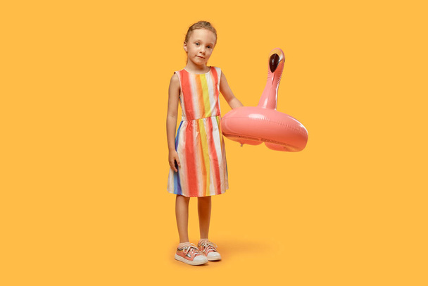 A full-length girl in summer in a dress with a pink swimming circle. - Foto, afbeelding
