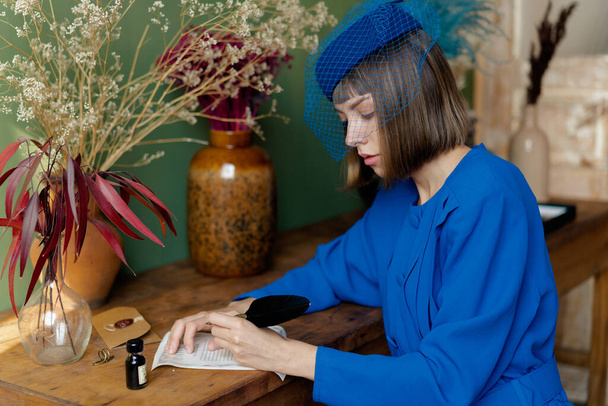 jonge vrouw in blauw ouderwetse jurk het schrijven van een briefje - Foto, afbeelding