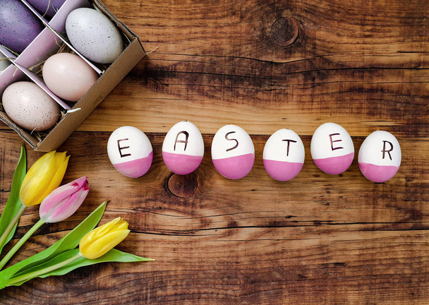 A top view of easter eggs with tulips on a wooden background - Photo, Image