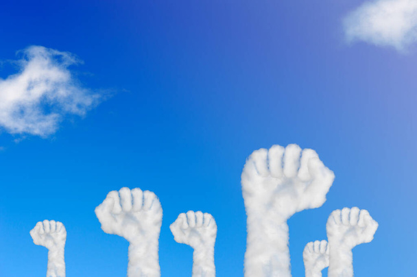 Wolkenförmige Hände hoben die Faust in den blauen Himmel. Konzept Arbeiterbewegung oder Firmenfeier. - Foto, Bild
