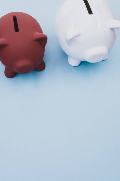 A vertical shot of piggy banks on a blue surface - Zdjęcie, obraz