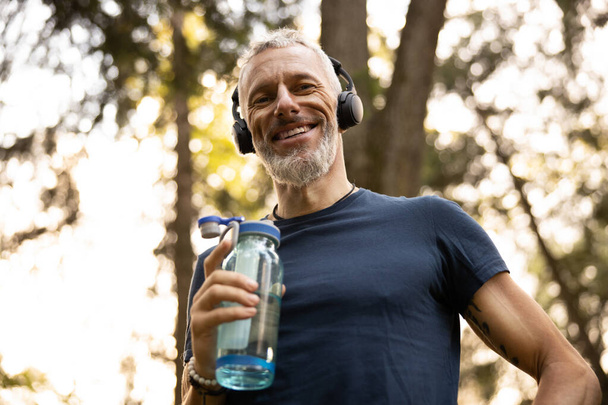 Happy bearded man with sporty bottle outdoors - Foto, Imagen