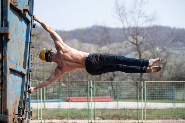 Muscular Man Doing Human Flag Exercise As Part Of Bodybuilding Training in Industrial Junk Yard - Foto, Imagen