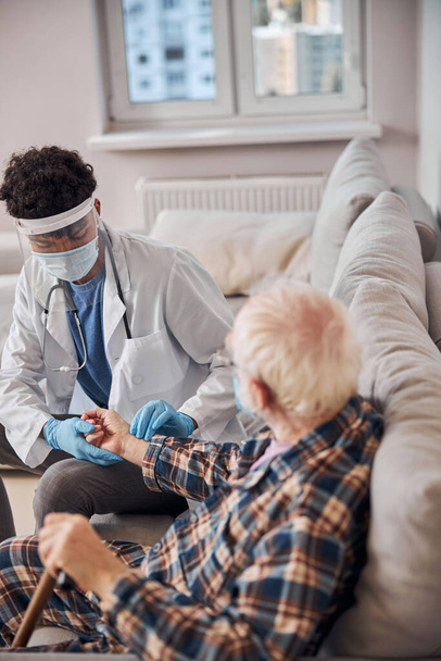Concentrated doctor performing a medical examination of a pensioner - Foto, afbeelding