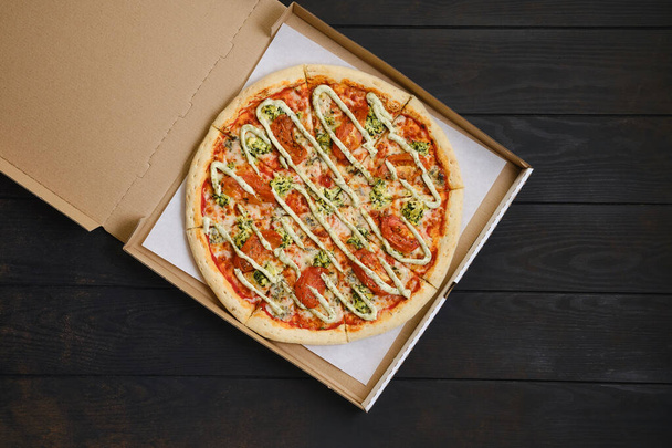 Top view of pizza with mozzarella, tomato, spinsch and mayonnaise in cardboard package - Fotó, kép
