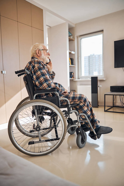 Senior citizen using his cellular phone indoors - Фото, изображение