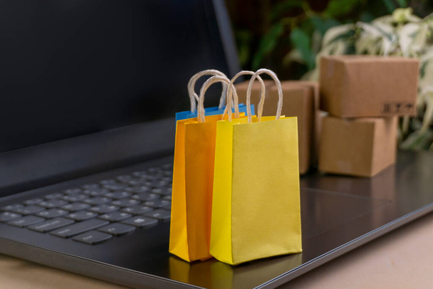 online shopping concept. little deliver boxes, smartphone, shopping bags, shopping bascket stand on laptop. copy space - Photo, Image