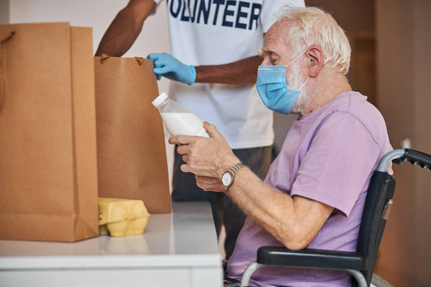 Volunteer in latex gloves taking foodstuffs out of the paper bag - Photo, Image