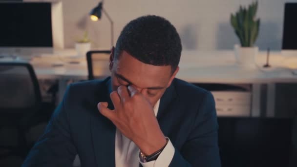 fatigué afro-américain homme d'affaires toucher les yeux au bureau la nuit - Séquence, vidéo