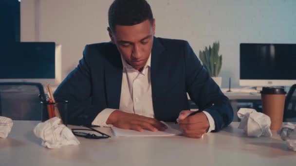 bouleversé homme d'affaires afro-américain écrit et froisser le papier au bureau  - Séquence, vidéo