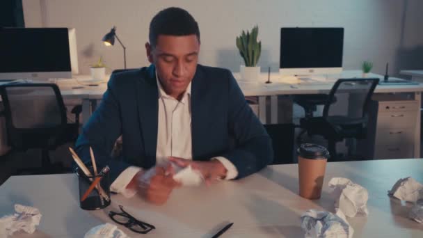 homme d'affaires afro-américain irrité repoussant tasse de papier près de papier froissé - Séquence, vidéo
