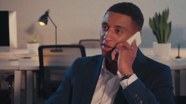 nuori afrikkalainen amerikkalainen liikemies puhuu älypuhelimella yöllä toimistossa - Materiaali, video