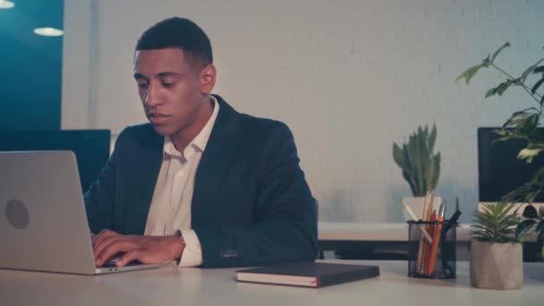 Африканский американский бизнесмен, работающий на ноутбуке ночью в офисе - Кадры, видео