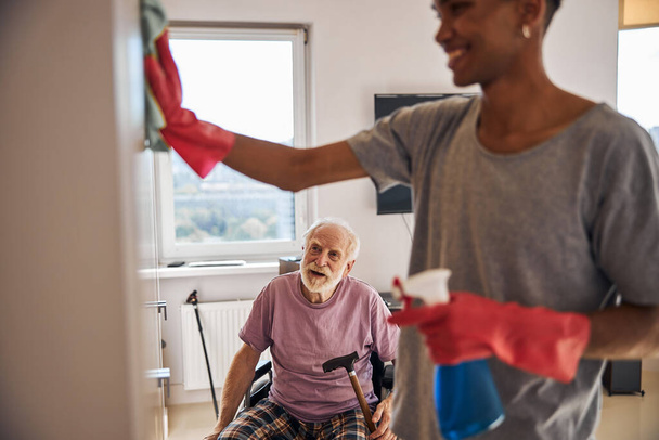 Volunteer helping a disabled person clean his home - Foto, immagini