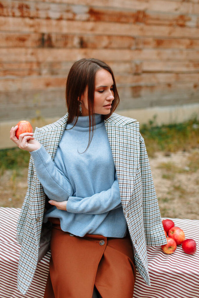 A girl sitting on a bench. Girl holding a red Apple. - Fotoğraf, Görsel