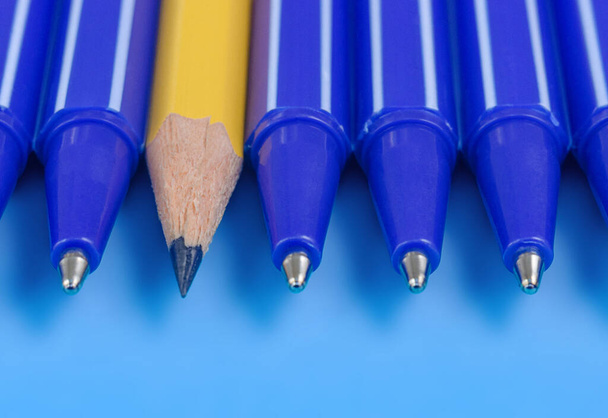 Jedna žlutá tužka a skupina modrých per. na modrém pozadí. Zavřít. Individualita a rozdílný koncept. - Fotografie, Obrázek