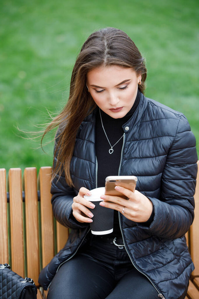 Young beautiful woman using smartphone in the park - Foto, Bild