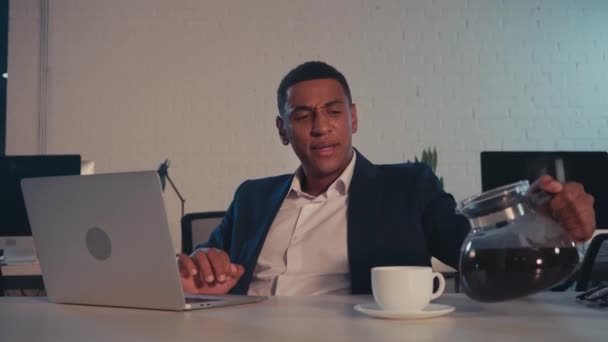 εξαντλημένος Αφροαμερικάνος επιχειρηματίας πίνοντας καφέ το βράδυ στο γραφείο - Πλάνα, βίντεο