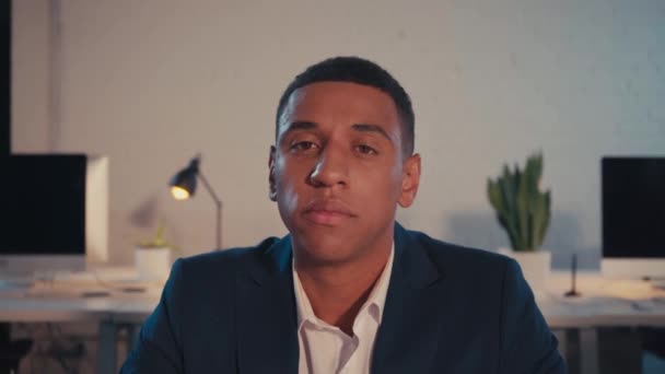 young african american businessman looking at camera in office at night - Footage, Video