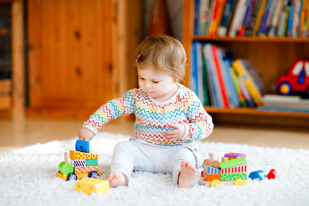 маленька дівчинка грає з освітніми дерев'яними іграшками вдома або в дитячій кімнаті. Тодлер з барвистим потягом. Дитина розважається з різними іграшками. Самотня дитина під час пандемії коронавірусу
 - Фото, зображення