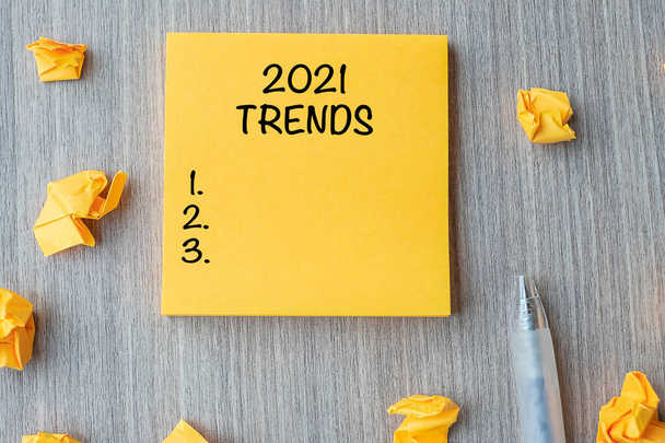 2021 Trends szó sárga hang tollal és porlasztott papír fa asztal háttér. Újév Újrakezdés, állásfoglalások, stratégia és cél koncepció - Fotó, kép