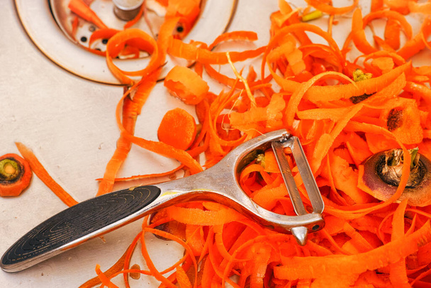 Peeler and carrot peels in a kitchen sink - Фото, зображення