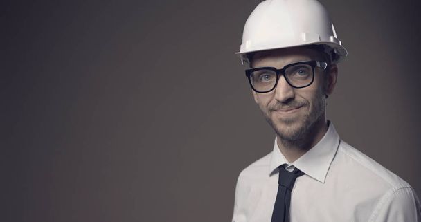 Confident architect smiling and wearing a safety helmet, construction industry and engineering concept - Zdjęcie, obraz