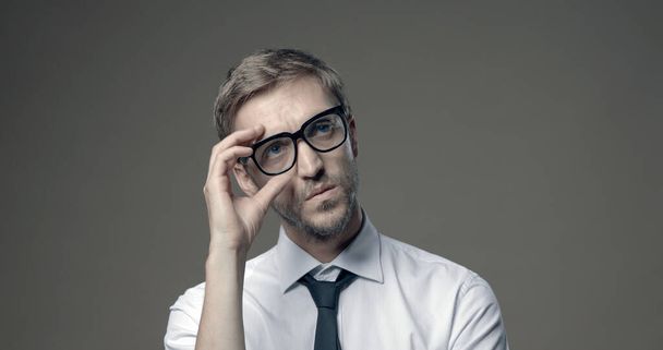 Komea nuori liikemies poseeraa ja säätää hänen silmälasit - Valokuva, kuva