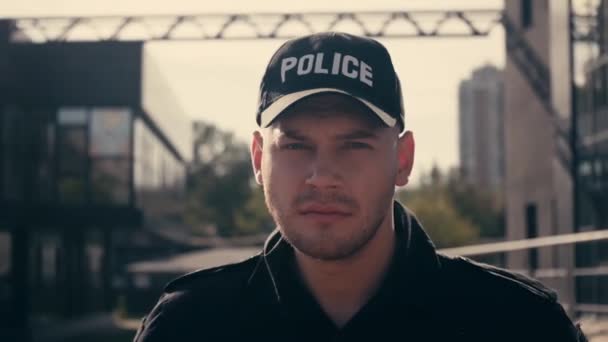 Policeman in uniform looking at camera on urban street  - Filmmaterial, Video