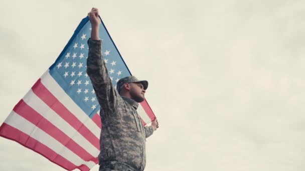 Vista basso angolo di soldato che tiene bandiera americana all'aperto  - Filmati, video