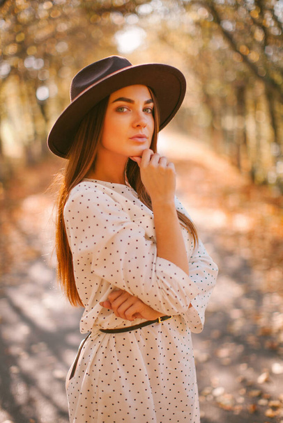 Girl walks in a dress and hat in the park. - Photo, image