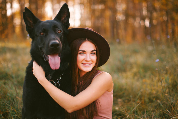 Tyttö mekko ja hattu istuu koiran kanssa puistossa - Valokuva, kuva