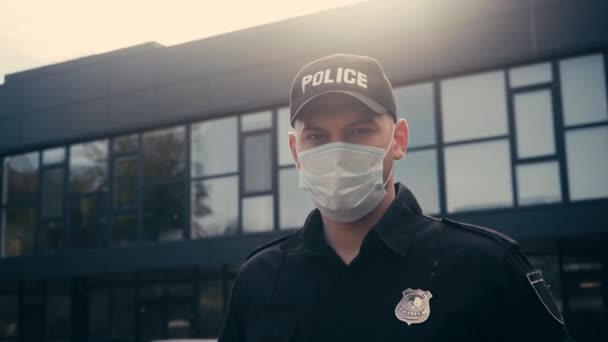 Policjant w masce medycznej patrząc na kamery na zewnątrz  - Materiał filmowy, wideo