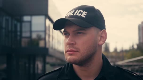 Policjant w czapce spaceru podczas patrolowania ulicy miejskiej  - Materiał filmowy, wideo