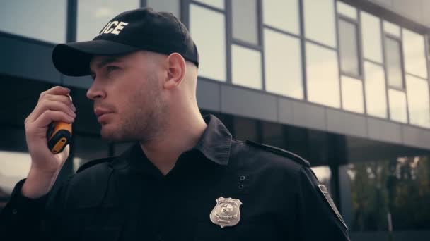 Un policier utilise un talkie-walkie debout à l'extérieur  - Séquence, vidéo