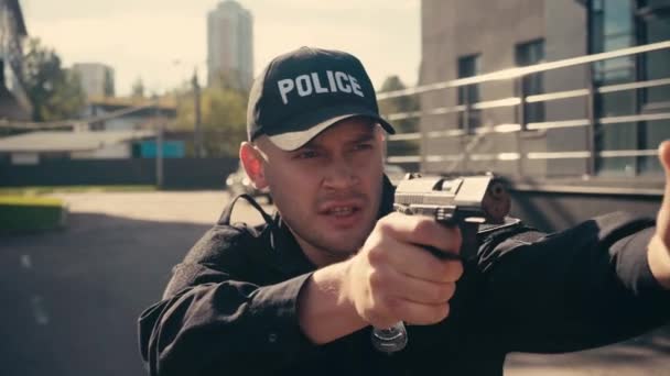 Agente di polizia che tiene la pistola e parla sulla strada urbana  - Filmati, video