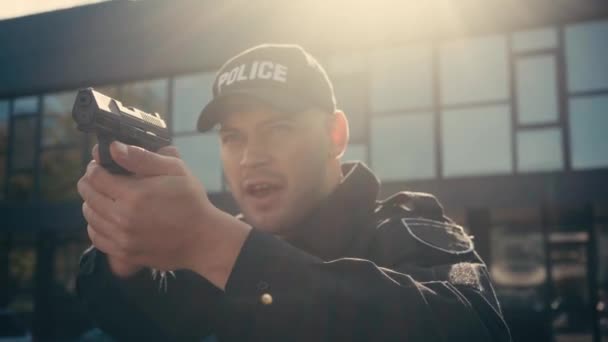 Pistolet w rękach policjanta mówiącego na ulicy miejskiej  - Materiał filmowy, wideo