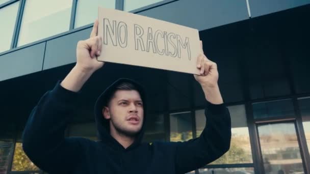Uomo in possesso di cartello senza razzismo lettering e parlare all'aperto  - Filmati, video