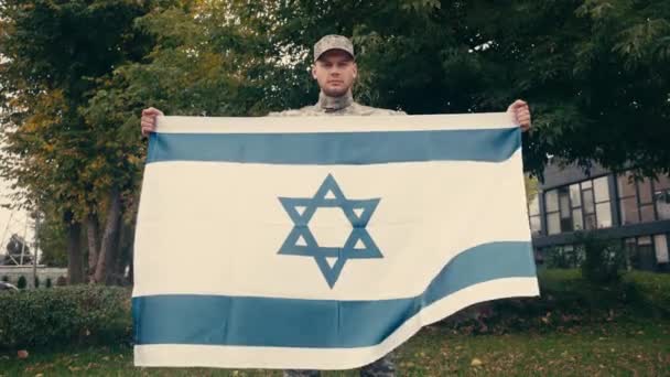 Soldado en uniforme sosteniendo bandera de Israel al aire libre  - Imágenes, Vídeo