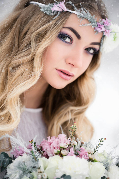 Winter bride in a snowy forest in the open air with beautiful flowers on her head and a bouquet. The concept of a winter wedding. Soft focus and blur effect. - Fotoğraf, Görsel