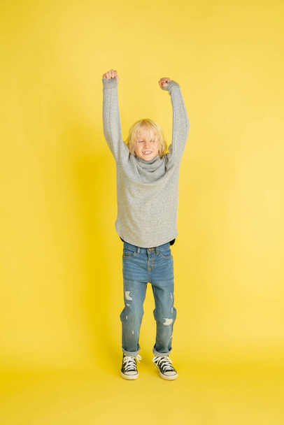 Portrait of little caucasian boy with bright emotions isolated on yellow studio background - Φωτογραφία, εικόνα