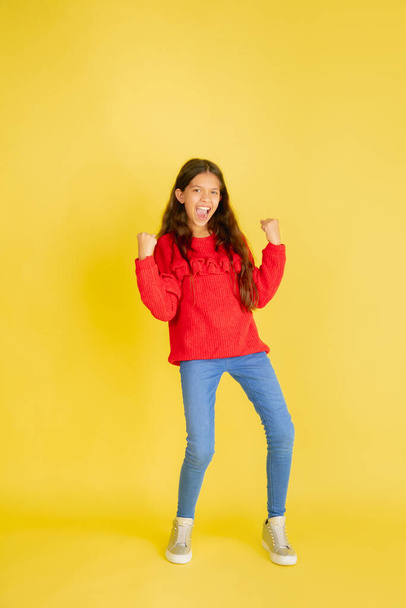 Portrait of young caucasian teen girl with bright emotions isolated on yellow studio background - Foto, imagen