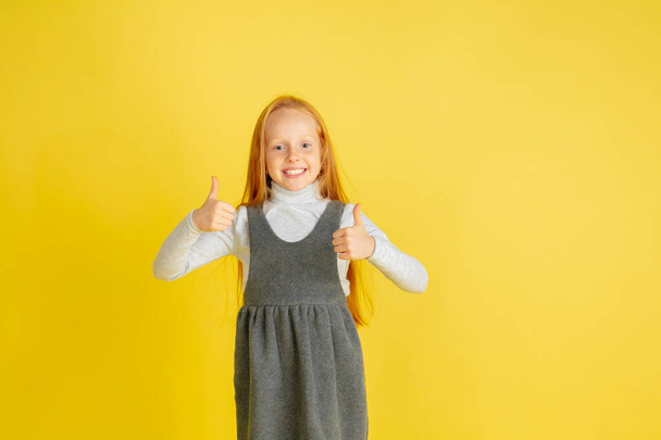 Portrait of little caucasian girl with bright emotions isolated on yellow studio background - Foto, Imagen