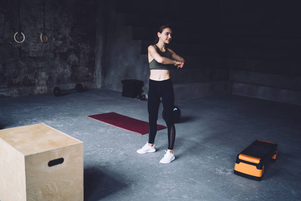 Positive caucasian female in trendy active wear exercising in gym prepare for cardio workout, brunette 20s woman doing warming up exercises slimming for perfect body muscular shape and figure - Fotografie, Obrázek