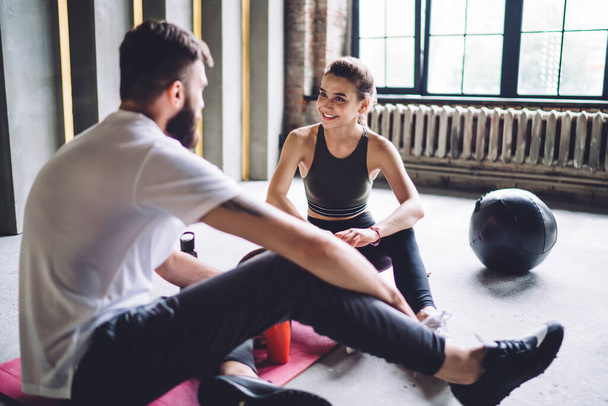 Happy young 20s woman having positive conversation with male trainer in gym discussing exercises and nutrition on consultancy, smiling couple in love satisfied with workout results share feedbacks - Fotoğraf, Görsel
