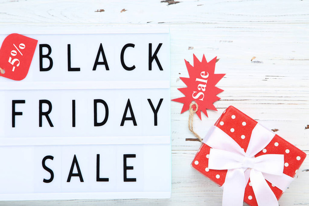 Lightbox with text Black Friday Sale with tags and gift box on wooden background - Foto, Bild