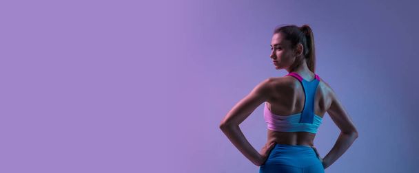 Young sportive woman training isolated on gradient studio background in neon light. athletic and graceful - Zdjęcie, obraz