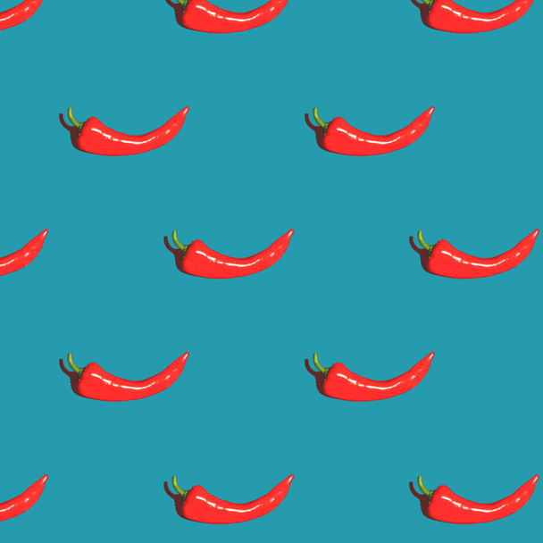 Seamless pattern made with red pepper over blue background. Colorful food backdrop. Minimal composition. - Фото, изображение