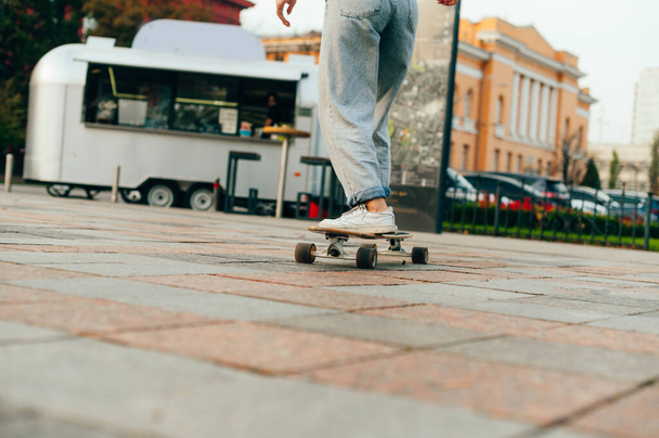 Primo piano, foto ritagliata. Gambe di una donna cavalca lungo la strada su un longboard. concetto di skateboard - Foto, immagini